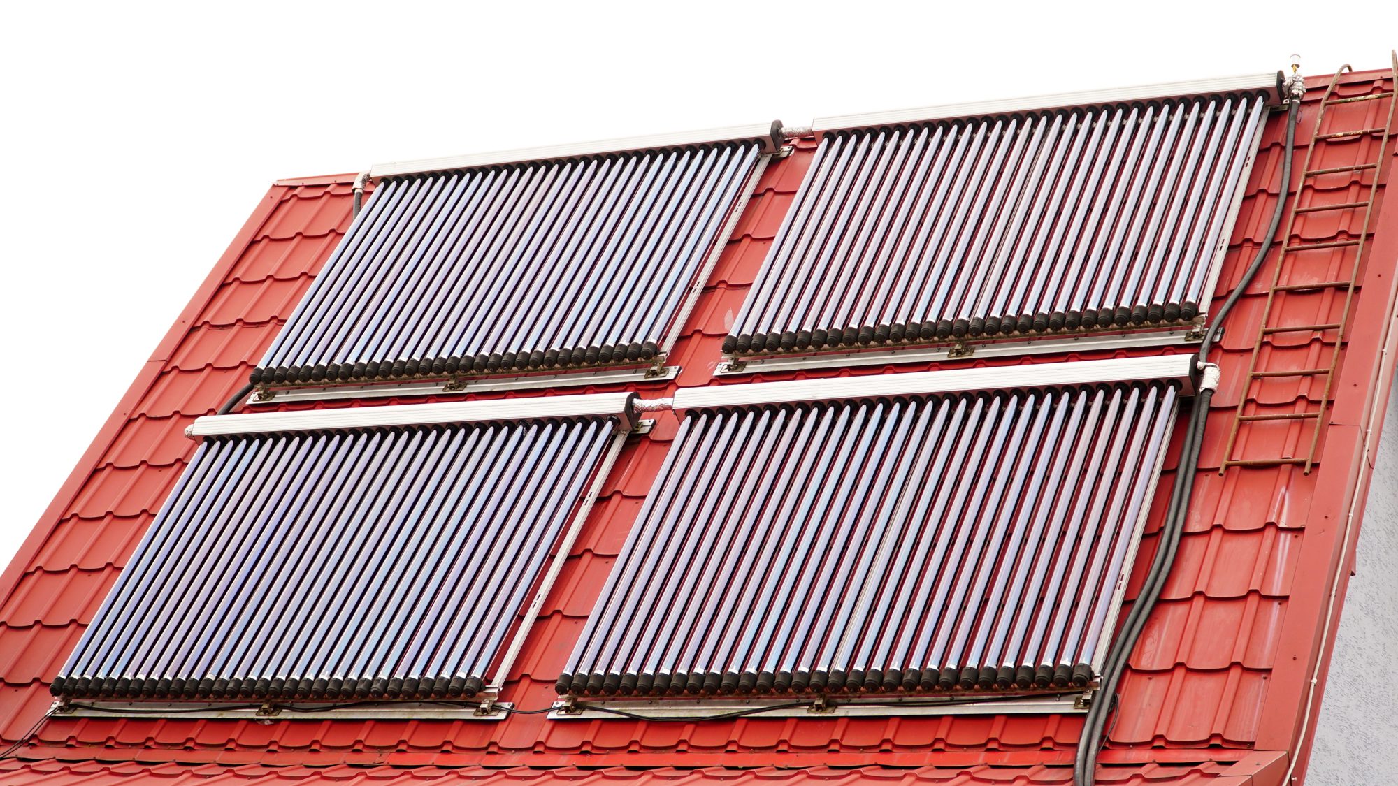 Solarthermie: Vakuumröhrenkollektoren auf einem roten Ziegeldach, montiert für Warmwasser und Heizungsunterstützung
