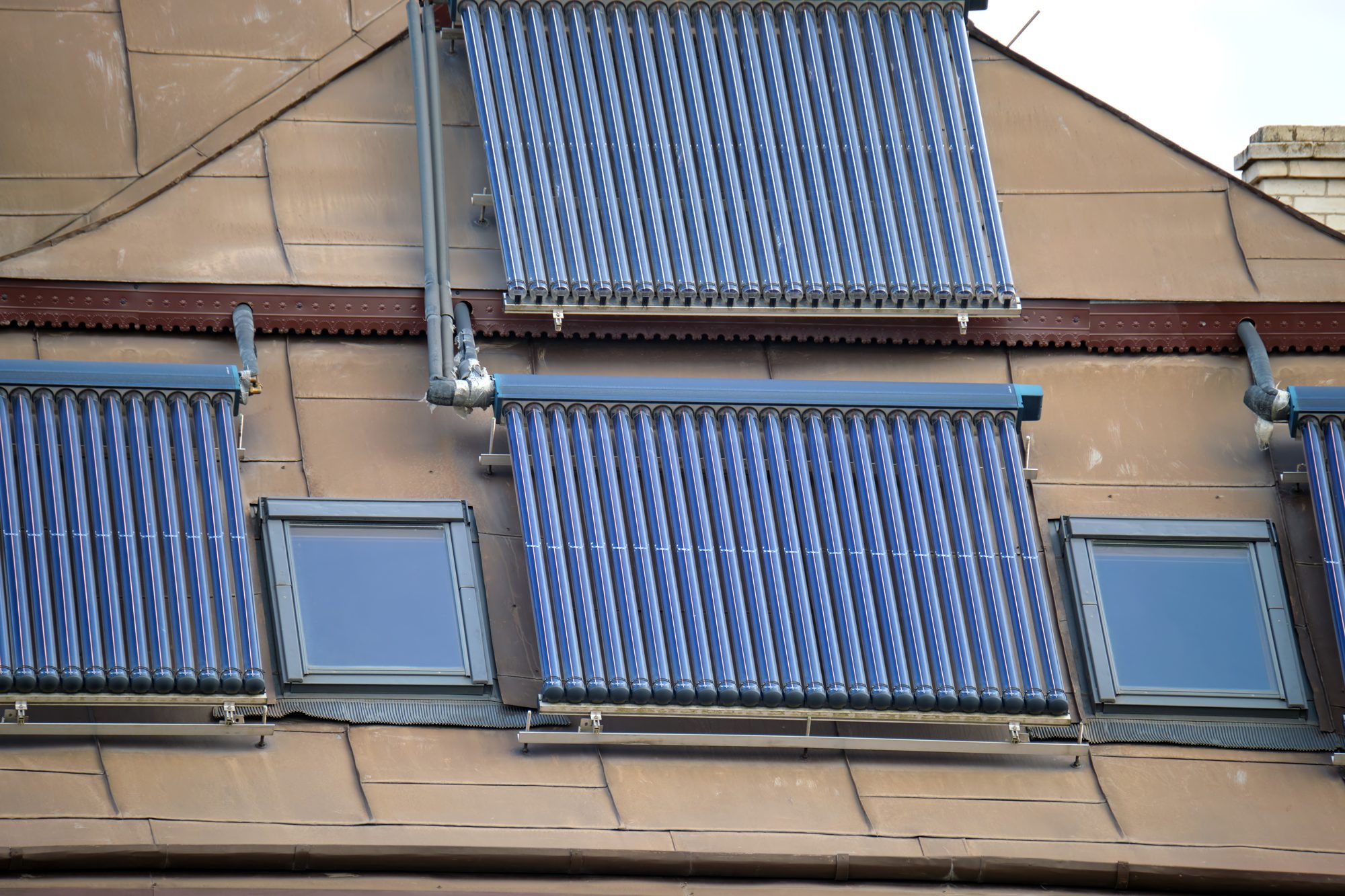 Solarthermie-Röhrenkollektoren auf einem Wohnhausdach mit Dachfenstern in Berlin